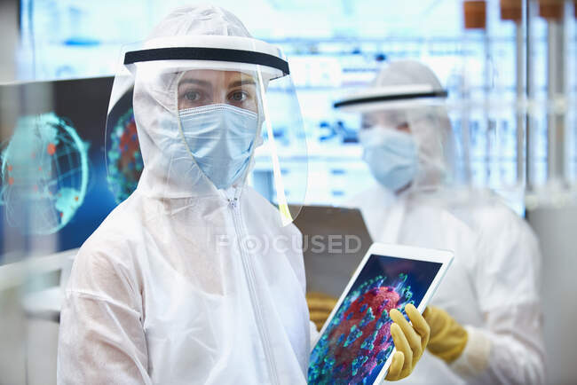 Женщина-ученый в чистом костюме, исследующая коронавирус — стоковое фото
