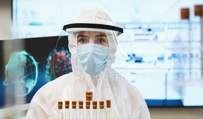 Porträt Wissenschaftlerin im sauberen Anzug untersucht Coronavirus-Impfstoff — Stockfoto
