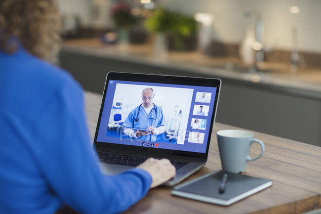 Mujer vídeo chat con los médicos en el ordenador portátil desde casa - foto de stock