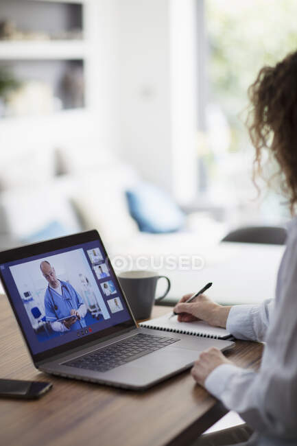 Mujer videoconferencia con médico en la pantalla del ordenador portátil - foto de stock