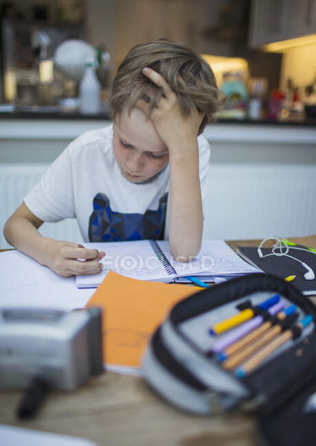 Сосредоточенное домашнее обучение мальчика за столом — стоковое фото