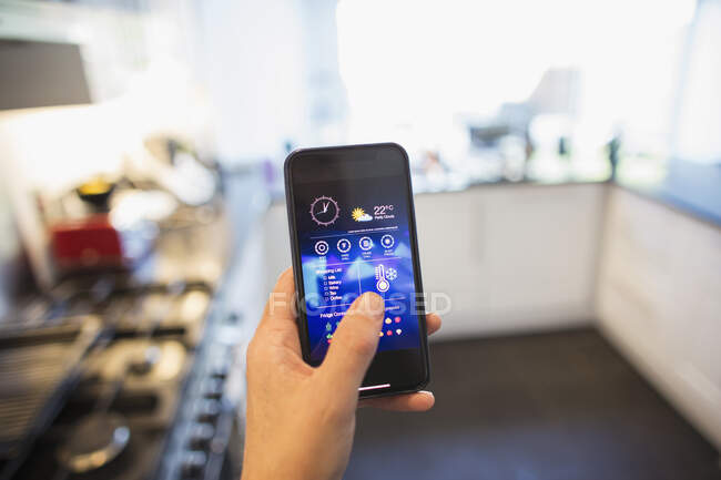 POV Man ajustando o controle do clima a partir de telefone inteligente na cozinha — Fotografia de Stock