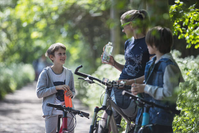 Madre e hijos bebiendo agua en bicicleta - foto de stock