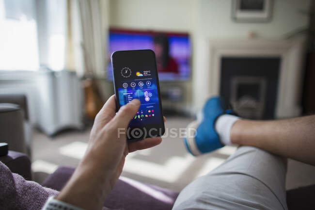 POV Man adjust temperature control on smart phone in living room — Stock Photo
