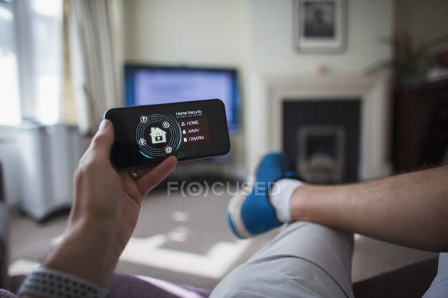 POV Mann checkt Haussicherheit auf Smartphone im Wohnzimmer — Stockfoto