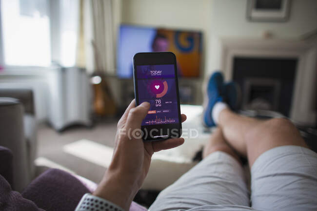 POV Homem verificando estatísticas de saúde no telefone inteligente na sala de estar — Fotografia de Stock