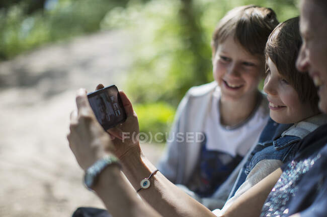 Mãe e filhos vídeo conversando com amigos no smartphone no parque — Fotografia de Stock