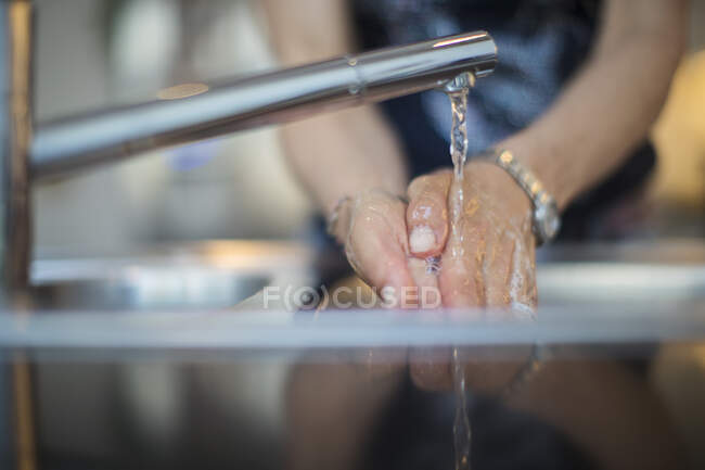 Крупным планом женщина моет руки у раковины на кухне — стоковое фото