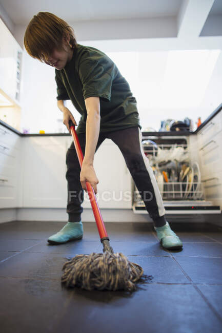 Menino esfregando chão da cozinha — Fotografia de Stock