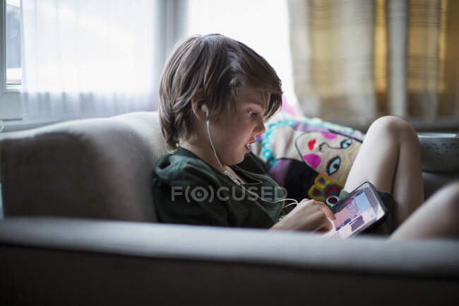 Boy with headphones using digital tablet in living room — Stock Photo