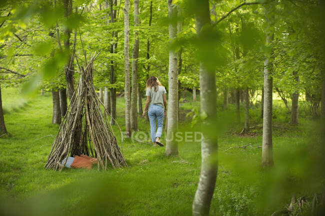 Mulher perto de teepee ramo na floresta — Fotografia de Stock