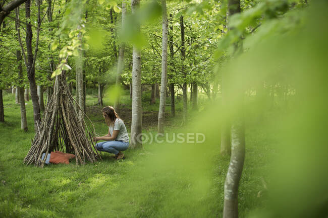 Mulher fazendo galho teepee na floresta — Fotografia de Stock