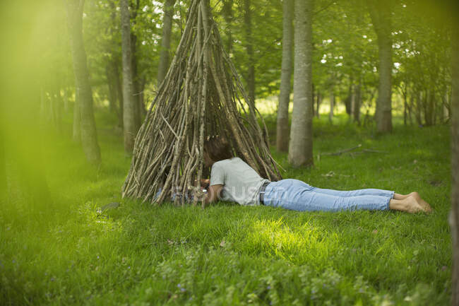 Woman laying at branch teepee in woodland — Stock Photo