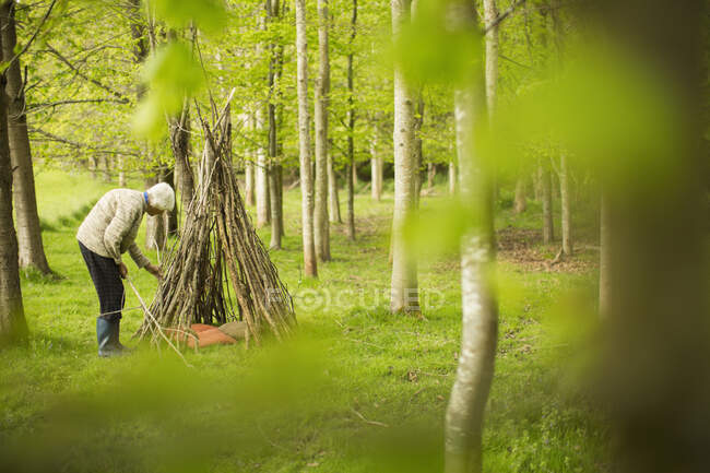 Seniorin bastelt Zweig-Tipi im Wald — Stockfoto