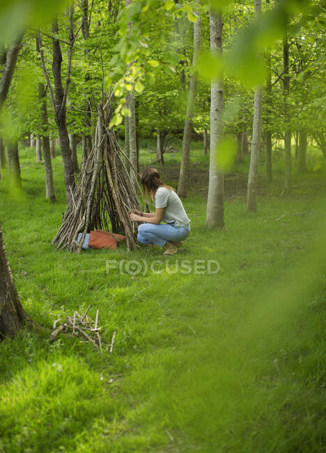 Mulher fazendo galho teepee na floresta — Fotografia de Stock