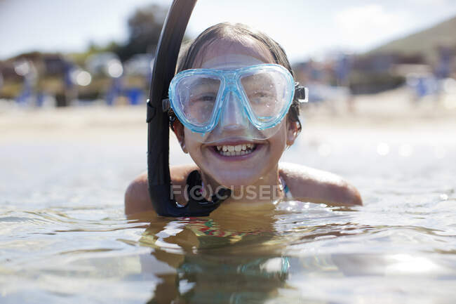 Happy girl wearing snorkel and goggles in ocean — Stock Photo