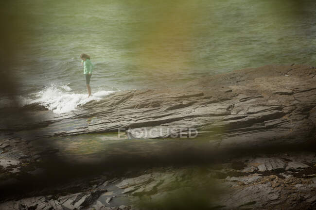 Mulher de pé sobre rochas na praia — Fotografia de Stock