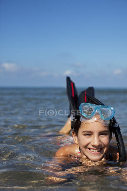 Menina sorridente com snorkel e óculos deitados no oceano — Fotografia de Stock