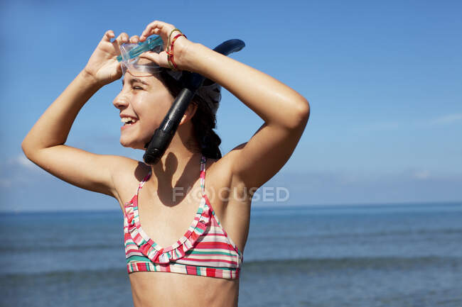 Menina sorridente vestindo snorkel e óculos na praia — Fotografia de Stock