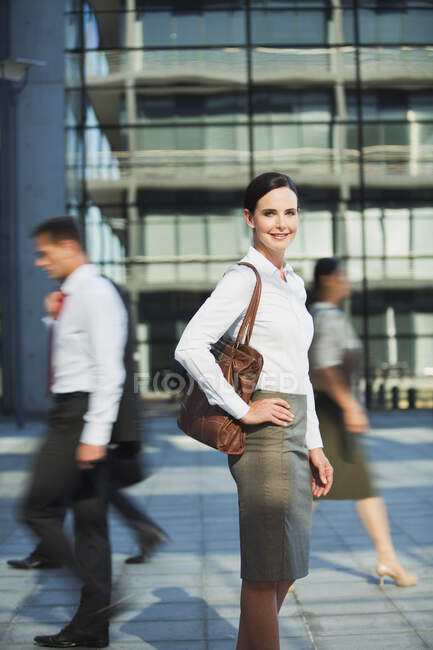 Smiling businesswoman on urban sidewalk — Stock Photo