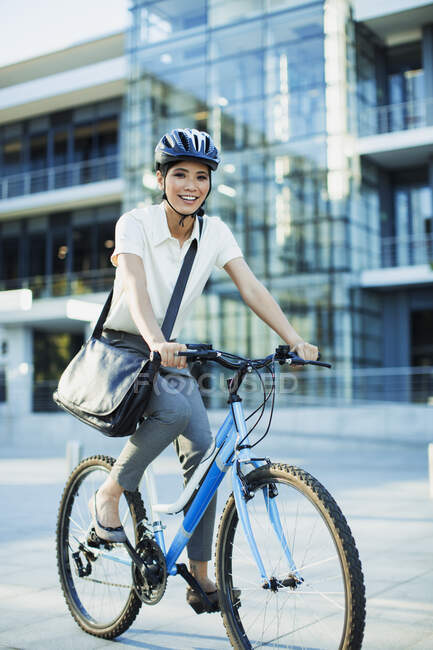 Mujer sonriente montar en bicicleta en la acera urbana - foto de stock