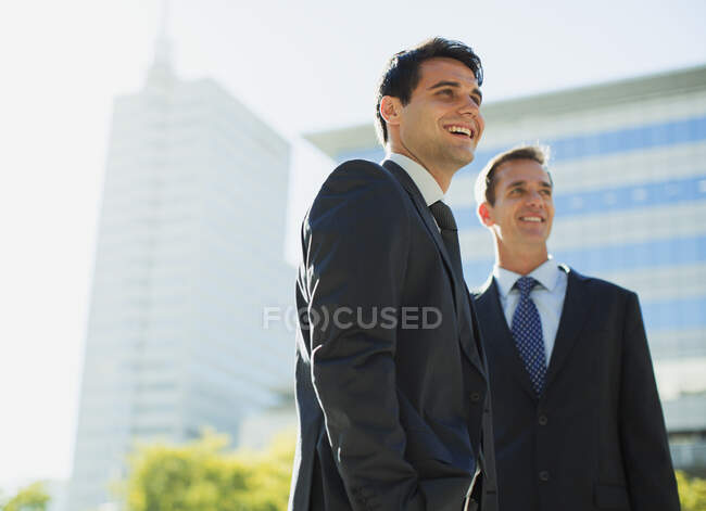 Hombres de negocios sonrientes frente a Highrise - foto de stock