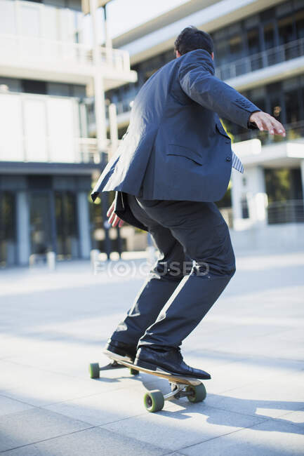 Бизнесмен катается на скейтборде по городской тротуаре — стоковое фото
