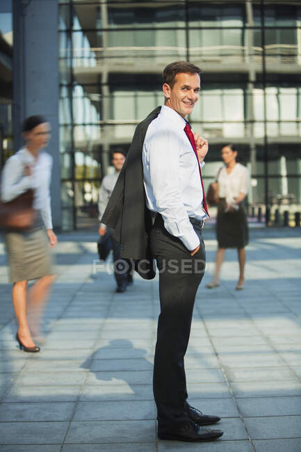 Homme d'affaires souriant devant les bâtiments urbains — Photo de stock