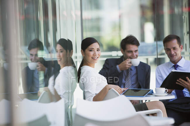 Улыбающаяся деловая женщина с коллегами в кафе на тротуаре — стоковое фото