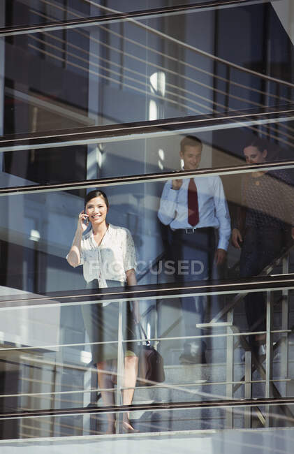 Усміхнена бізнес-леді використовує мобільний телефон у вікні — стокове фото