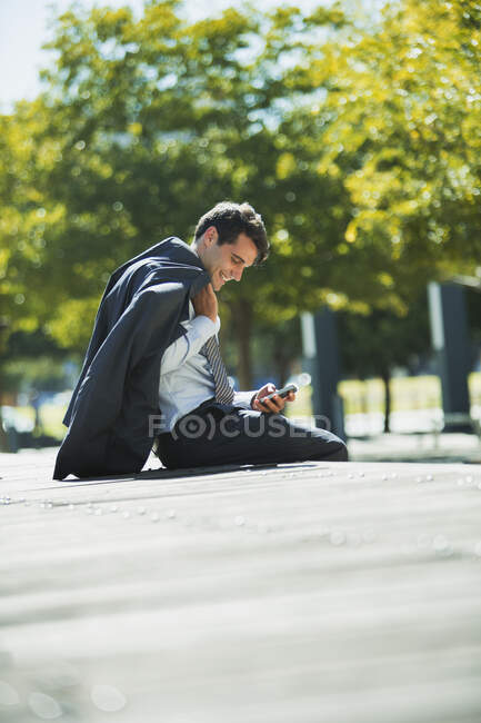 Smiling businessman using cell phone in park — Stock Photo