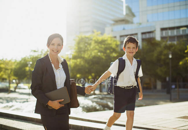 Sorrindo empresária andando com filho ao ar livre — Fotografia de Stock