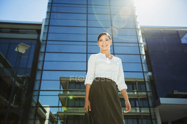 Mujer de negocios sonriente por debajo de Highrise - foto de stock