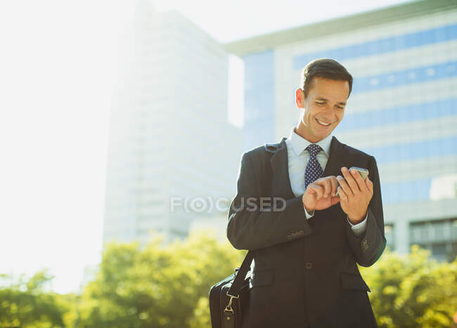 Mensajería de texto de hombre de negocios fuera del edificio urbano - foto de stock