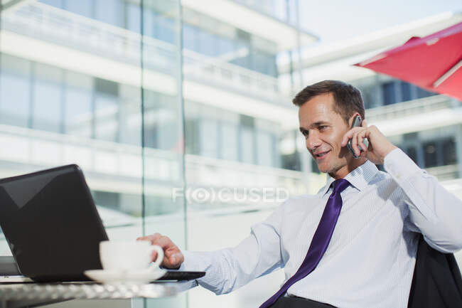 Бізнесмен використовує ноутбук і розмовляє на мобільному телефоні в офісі — стокове фото
