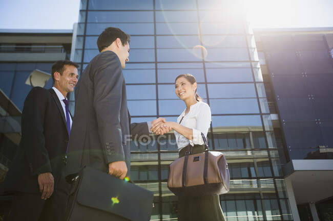 Business people shaking hands under highrise — Stock Photo