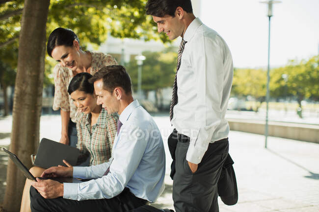 Empresários usando laptop no parque urbano — Fotografia de Stock