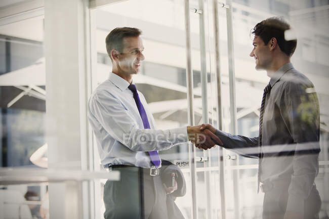 Hombres de negocios estrechando la mano en la oficina - foto de stock