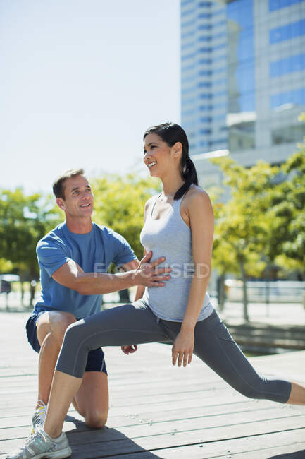 Personal trainer guiding woman with lunges in urban park — Stock Photo