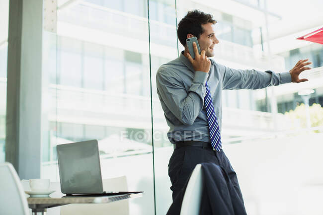 Uomo d'affari che parla al cellulare alla finestra — Foto stock