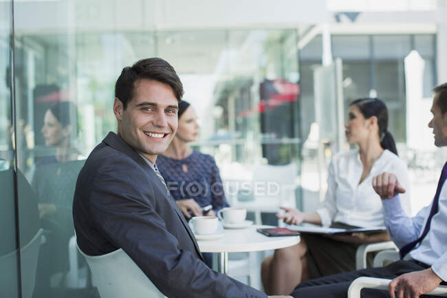 Smiling businessman in meeting at sidewalk cafe — Stock Photo