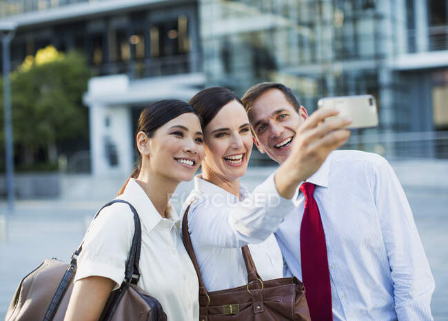 Smiling business people taking self-portrait outdoors — Stock Photo