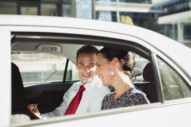 Homme d'affaires et femme d'affaires parlant sur le siège arrière de la voiture — Photo de stock