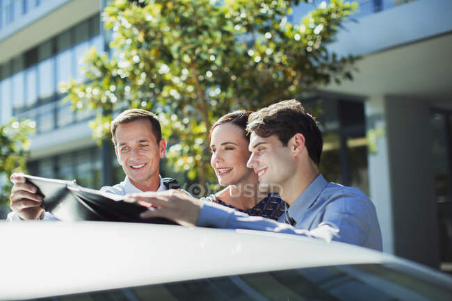Pessoas de negócios olhando para papelada em cima do carro — Fotografia de Stock