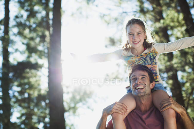 Feliz hija sobre los hombros de los padres en el bosque - foto de stock
