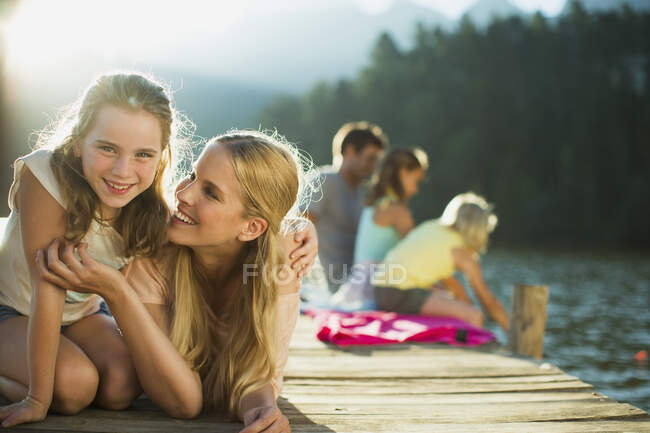 Sorrindo mãe e filha na doca sobre o lago — Fotografia de Stock