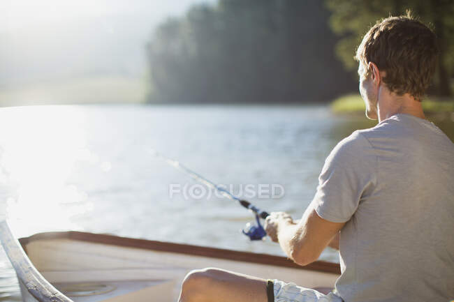 Homem de pesca em barco a remos em lago calmo — Fotografia de Stock