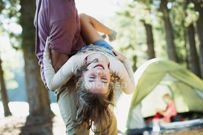 Father carrying happy daughter outside tent in woods — Stock Photo