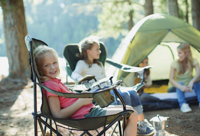 Lächelndes Mädchen sitzt auf Campingplatz im Stuhl — Stockfoto