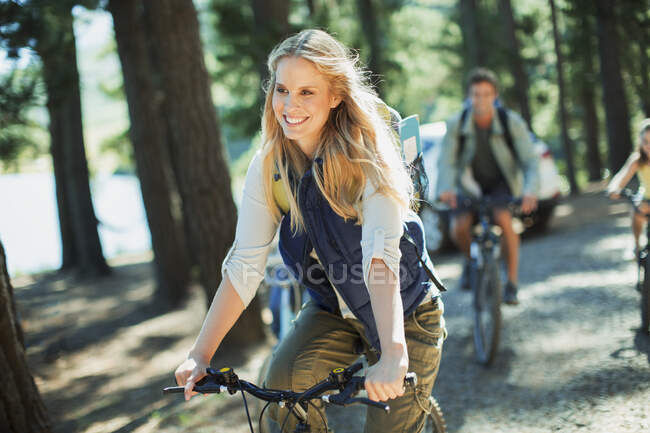 Femme souriante vélo équitation dans les bois — Photo de stock